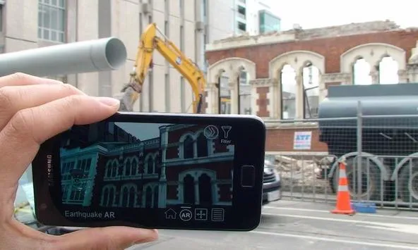 Phone held up to an earthquake-damaged building site, showing the CityViewAR app overlaying a reconstructed 3D view of the original building